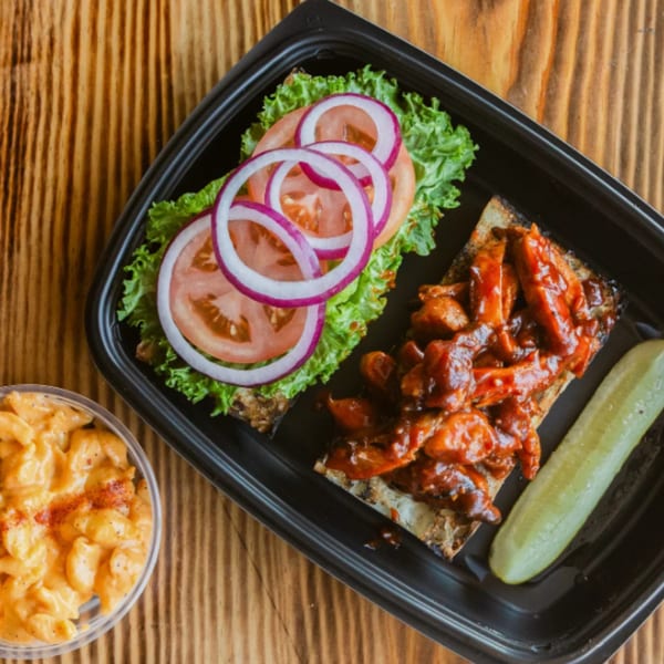 Ludy's BBQ chicken sandwich with lettuce, tomato, onion, a pickle, and mac and cheese.