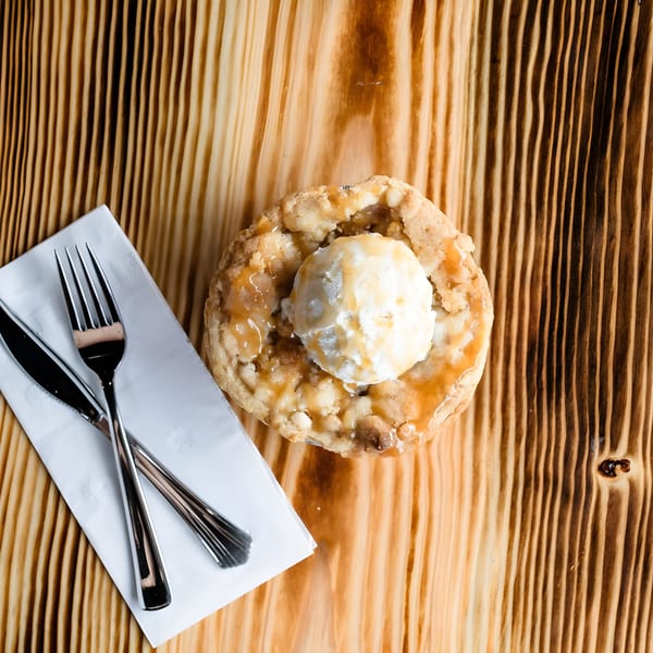 Overhead view of a Ludy's BBQ apple cobbler with vanilla ice cream and caramel drizzle.
