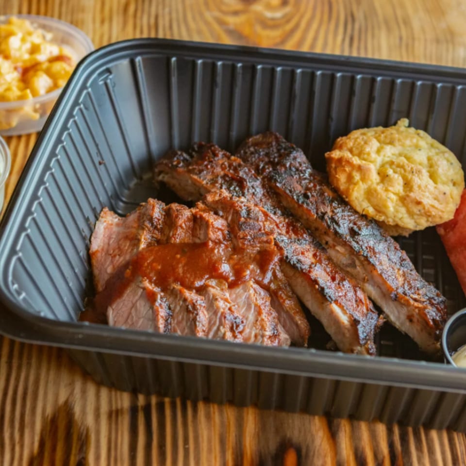 Ludy's BBQ ribs and sliced brisket with sauce, a biscuit, and mac and cheese.